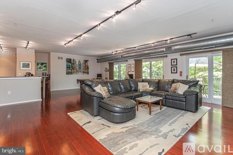 A spacious living room with a black leather sofa and a wooden coffee table.
