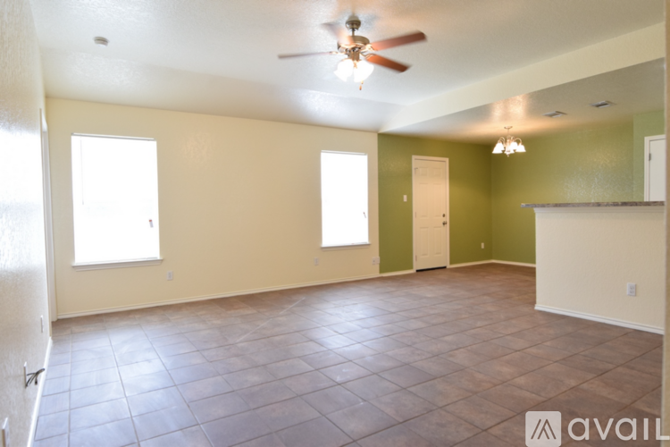 A spacious room with tile flooring and a ceiling fan.