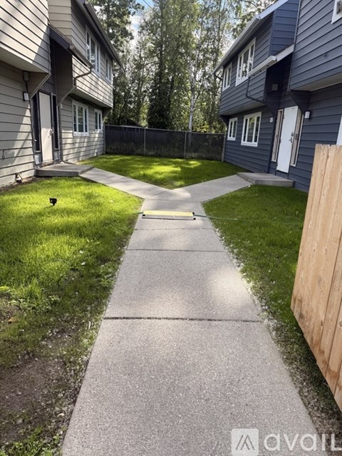 A concrete pathway leads from a grassy area to a wooden fence.