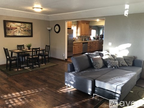 A living room with a grey couch and a dining table with chairs.