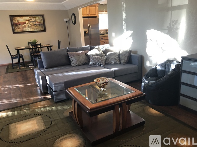 A living room with a grey couch and a glass coffee table.