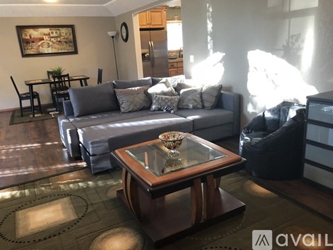 A living room with a grey couch and a glass coffee table.