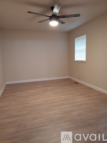 A room with a ceiling fan and wooden flooring.