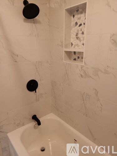 A bathroom with a white tub and a black faucet.