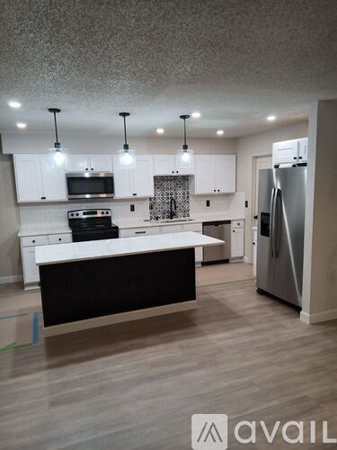 A modern kitchen with white cabinets and a black island.