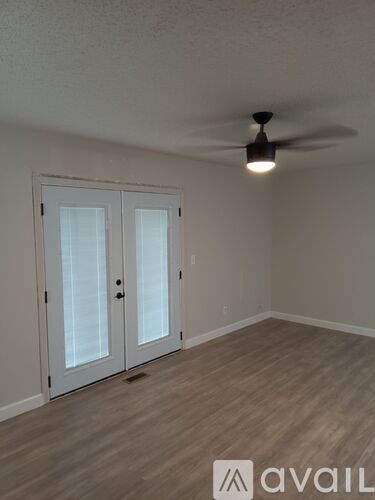 A room with a ceiling fan and two doors.