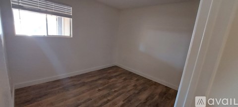 A room with wooden flooring and a window with blinds.