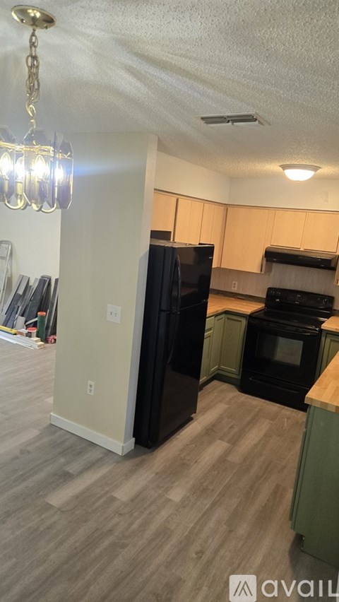 A kitchen with black appliances and wooden floors.