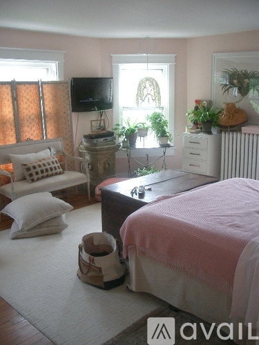 A bedroom with a bed, chair, and window.