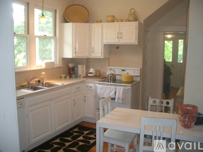 A kitchen with white cabinets and a black and white rug.