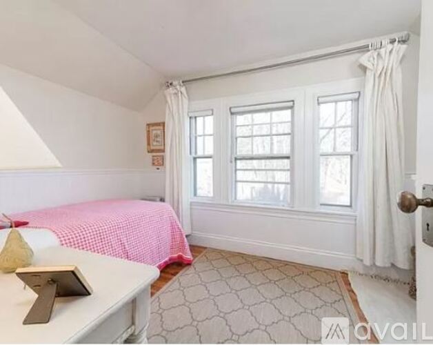 A bedroom with a pink bedspread and a white dresser.