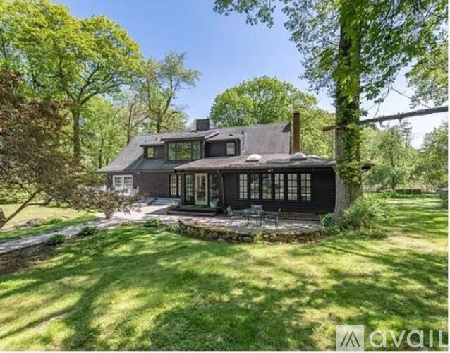 A house with a black exterior is surrounded by greenery.
