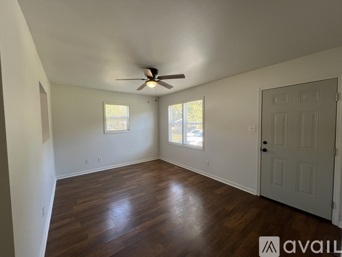 A room with a ceiling fan and wooden flooring.