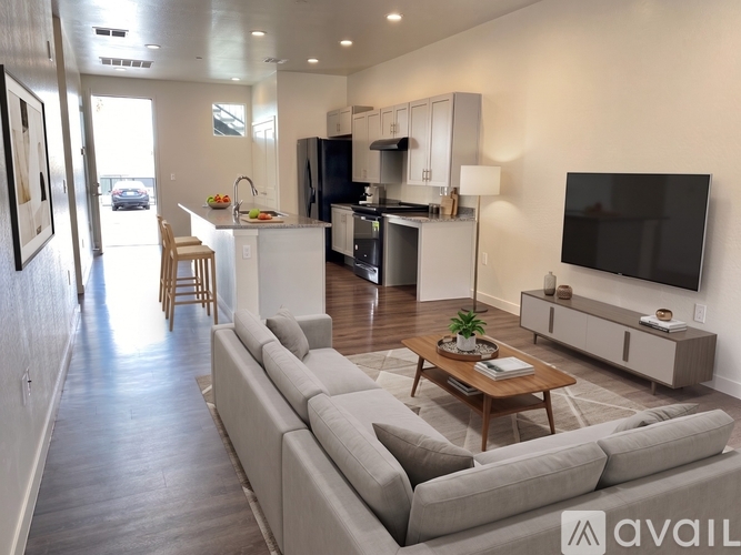 A modern living room with a grey sofa and a television on the wall.
