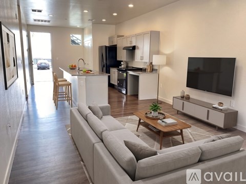 A modern living room with a grey sofa and a television on the wall.