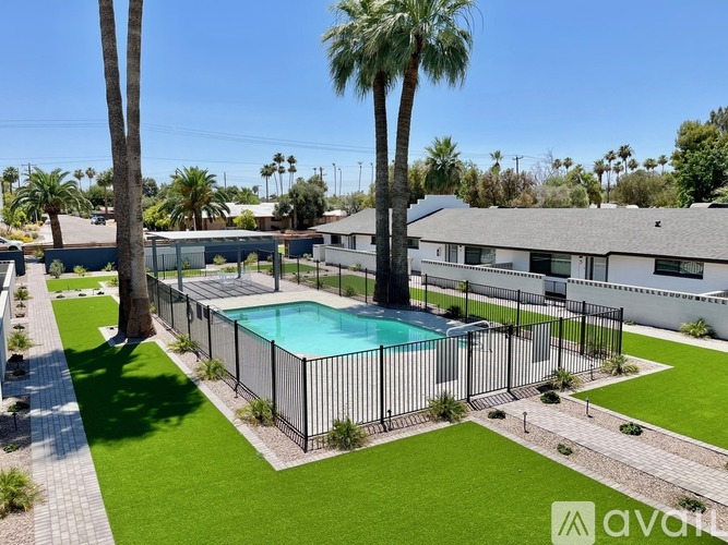 A pool surrounded by a black fence with a house in the background.