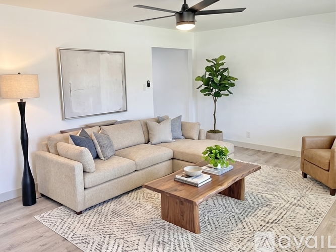 A living room with a beige couch, a coffee table, a floor lamp, and a plant.