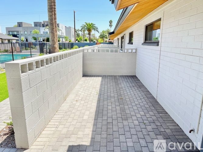 A white wall with a brick patterned walkway in front of a house.