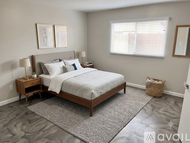 A bedroom with a large bed, a nightstand, and a window with blinds.