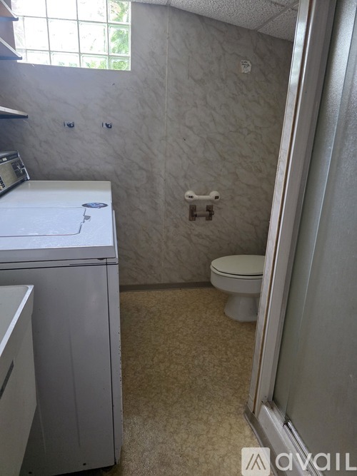A small bathroom with a toilet and a washing machine.