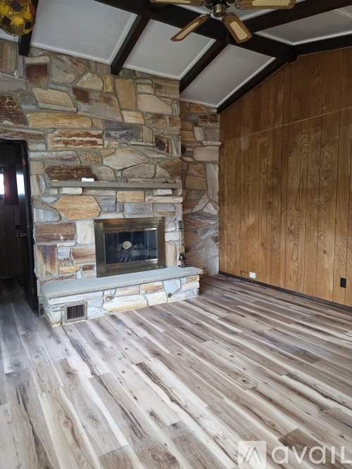 A room with wooden floors and a stone fireplace.