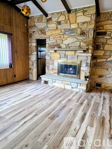 A room with a stone fireplace and wooden floors.