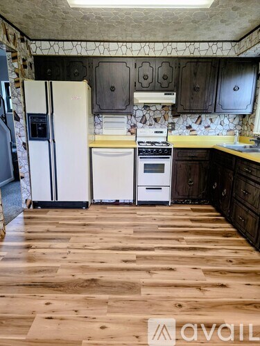 A kitchen with wooden floors and a white fridge.