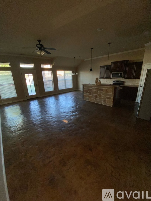 A living room with a fan and a kitchen area in the background.