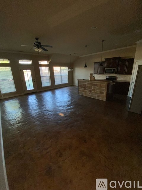 A living room with a fan and a kitchen area in the background.