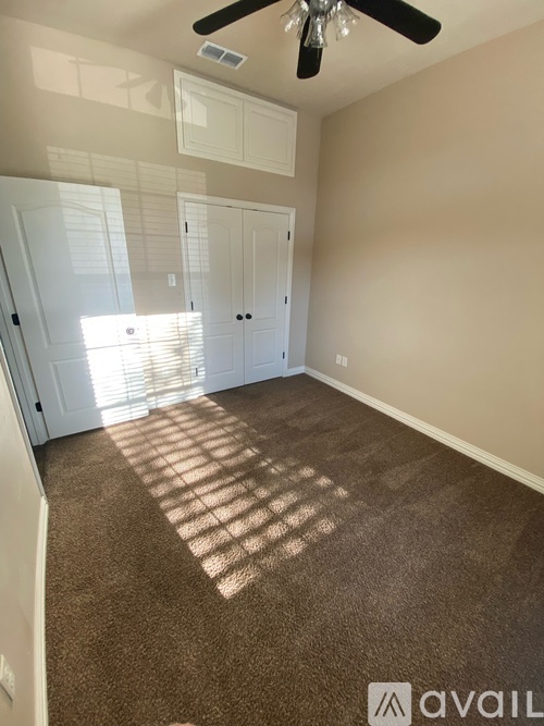 A room with a ceiling fan and carpeted floor.
