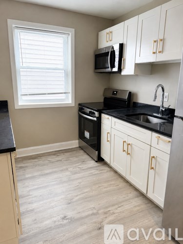 A kitchen with white cabinets and black countertops.