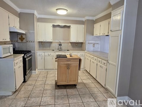 A kitchen with white cabinets and a wooden island.
