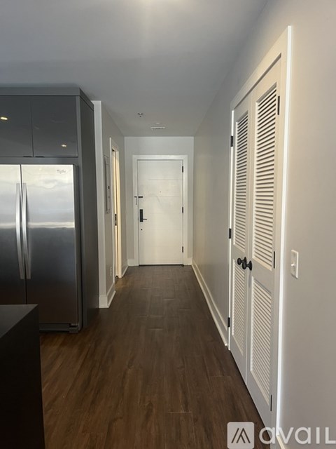 A long hallway with a refrigerator on the left and a door at the end.