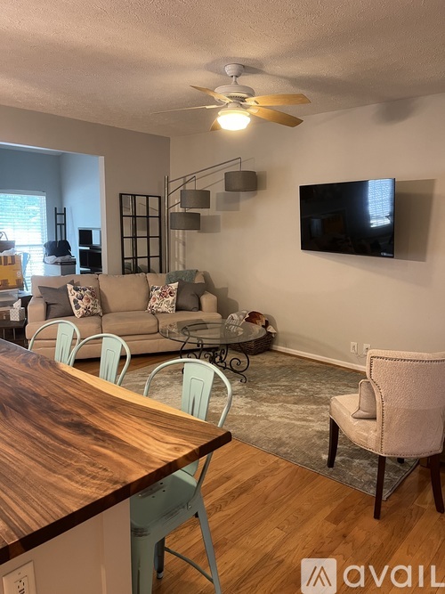 A living room with a grey couch, a wooden table, and a television mounted on the wall.