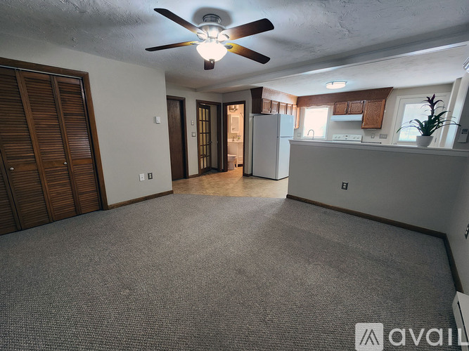 A spacious living room with a ceiling fan and carpeted floor.