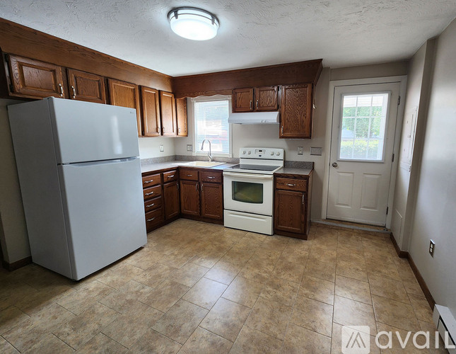 A kitchen with a white refrigerator and brown cabinets.