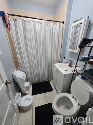 A bathroom with a toilet, sink, and shower curtain.