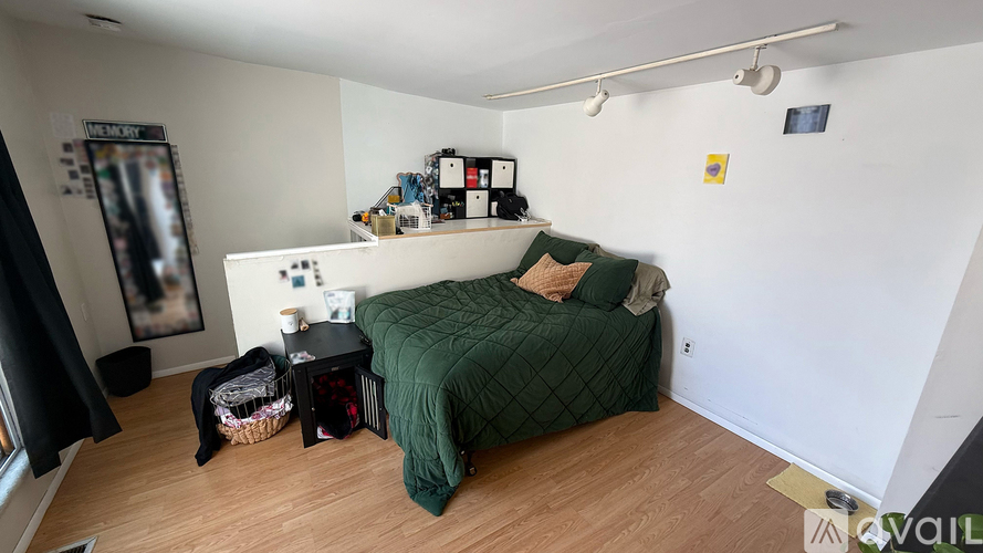 A bedroom with a green bed and a white wall.