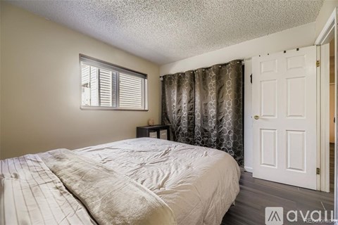 A bedroom with a bed, a window with curtains, and a door.