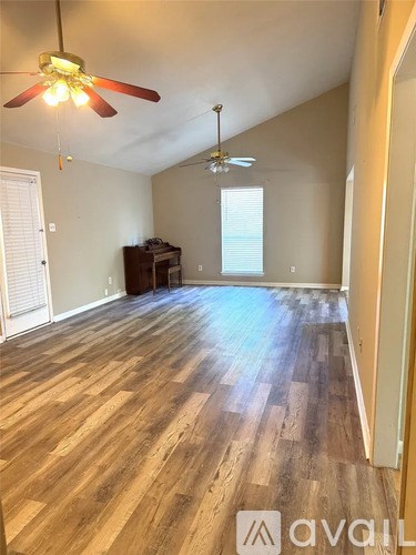 A room with wooden flooring and two ceiling fans.
