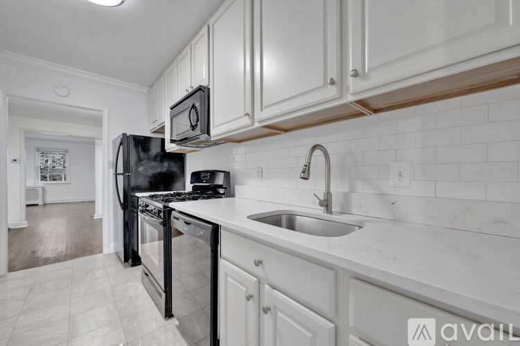 A kitchen with white cabinets and a black refrigerator.