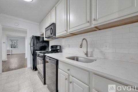 A kitchen with white cabinets and a black refrigerator.
