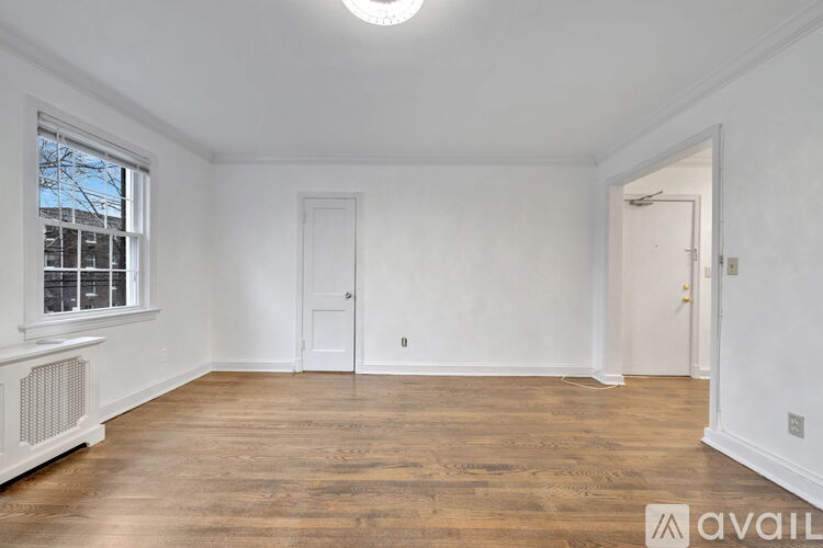 A room with wooden floors and white walls, with a window on the left side.