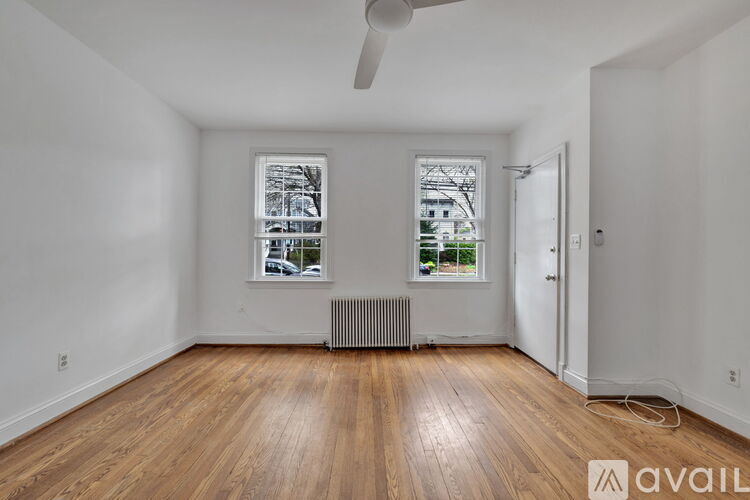 A room with wooden floors and a window with a view of a building outside.