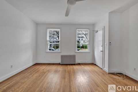 A room with wooden floors and a window with a view of a building outside.