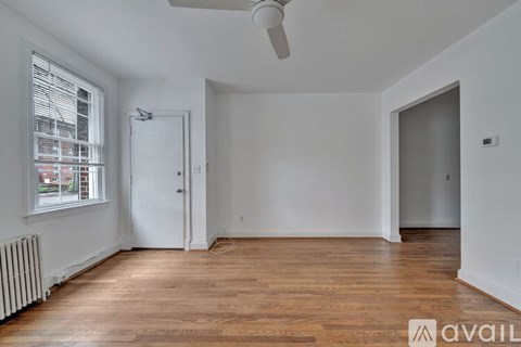 A room with wooden floors and white walls, with a window on the left side.