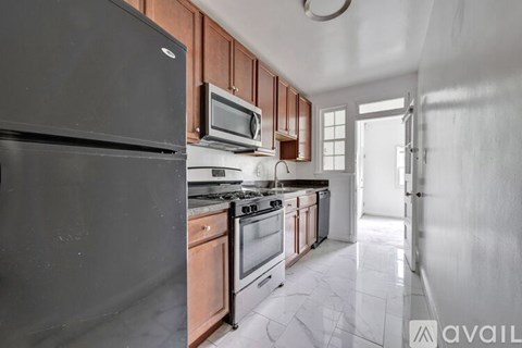A kitchen with a black fridge, microwave, and stove top oven.