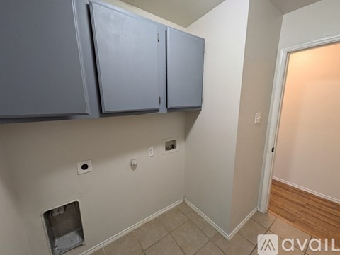 A kitchen area with grey cabinets and a white wall.