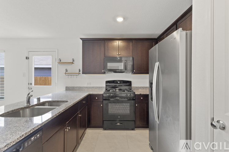 A modern kitchen with dark brown cabinets and a stainless steel refrigerator.