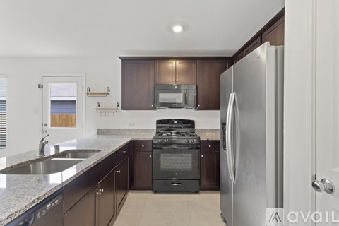 A modern kitchen with dark brown cabinets and a stainless steel refrigerator.
